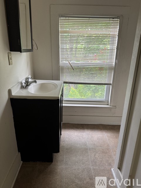 A bathroom with a sink and a window with blinds.