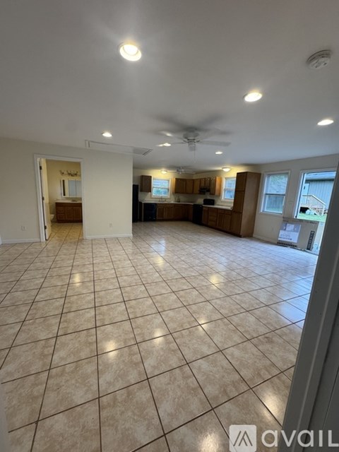 A spacious room with tiled flooring and a ceiling fan.