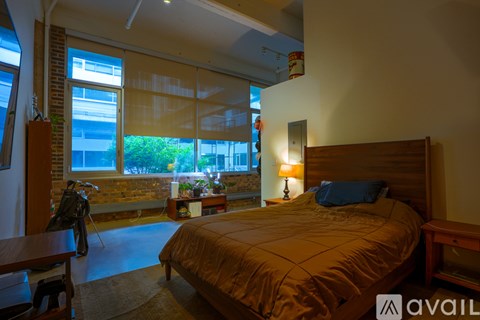 A bedroom with a large bed and a view of a balcony with plants.