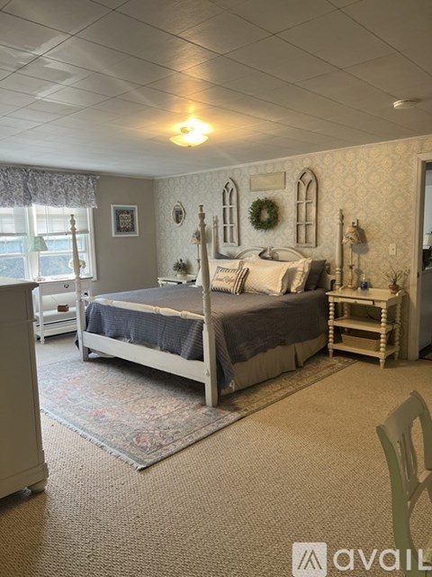A bedroom with a bed, chair, and window.