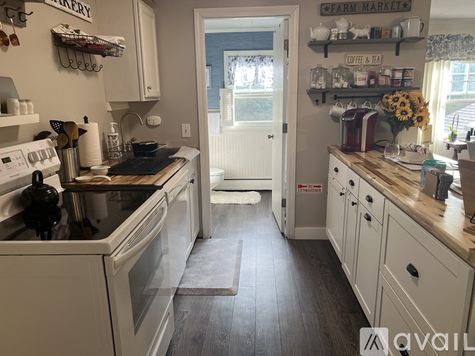 A kitchen with white appliances and wooden floors.