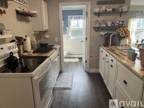 A kitchen with white appliances and wooden floors.
