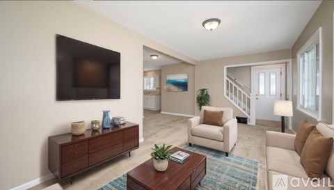 A living room with a brown coffee table and a brown cabinet with a flat screen TV mounted on the wall.