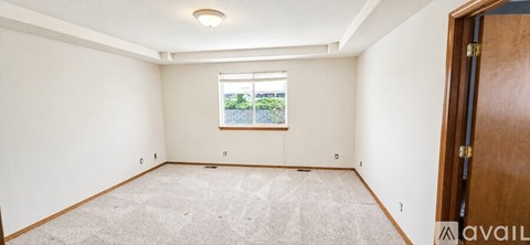 A room with a window and a carpeted floor.