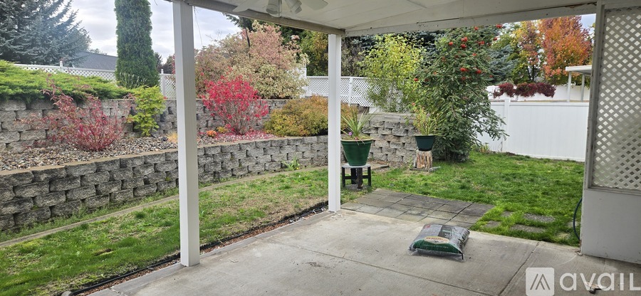 A patio with a table and chairs is surrounded by a stone wall and trees.