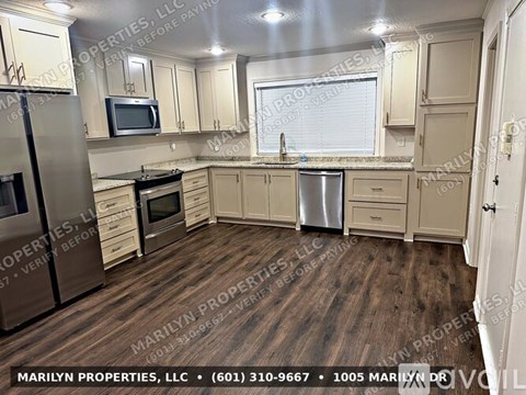A kitchen with wooden floors and beige cabinets.