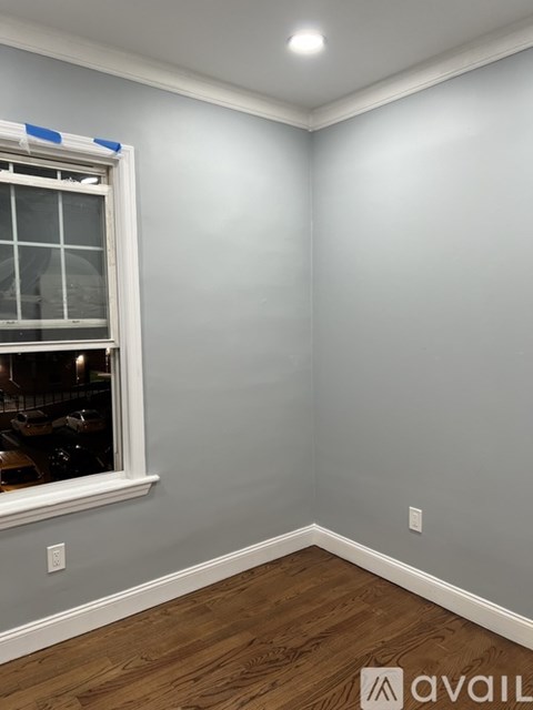 A room with a window and a wooden floor.