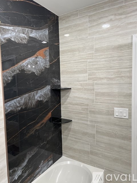 A bathroom with a marble and tile wall.