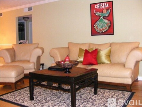 A living room with a couch, chair, coffee table, and a picture of a woman on the wall.
