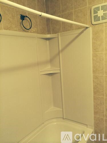 A white bathtub with a shower head and a grab bar.