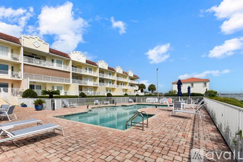 A pool area with sun loungers and a building in the background.