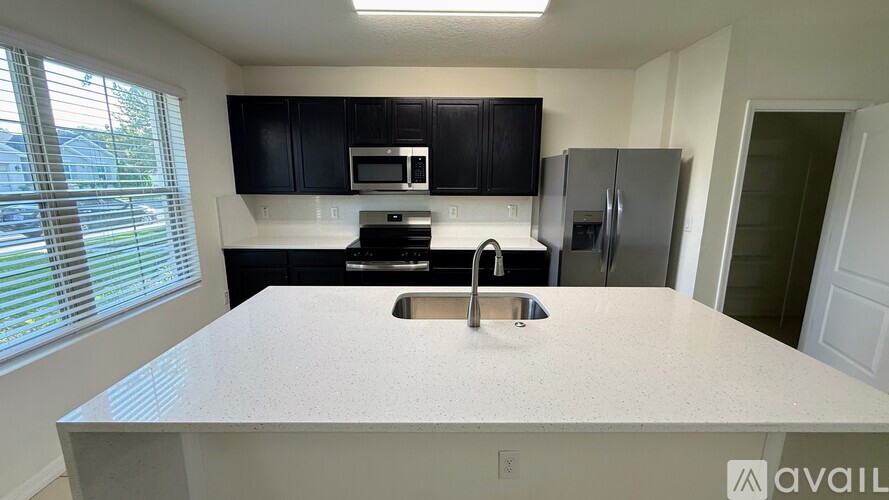 A kitchen with a white countertop and black cabinets.