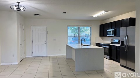 A kitchen with white cabinets and black appliances is available for rent.