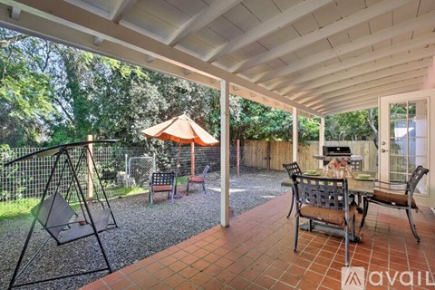 A patio with a swing set and a table set up for dining.