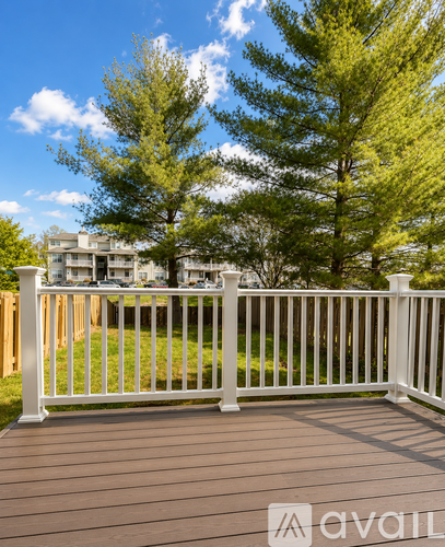 A deck with a white railing and a building in the background.