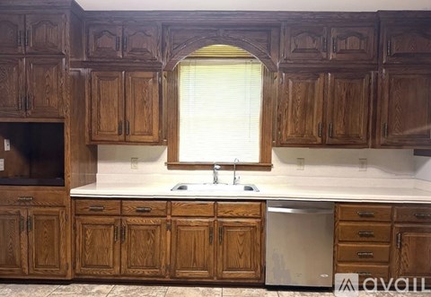 A kitchen with wooden cabinets and a window above the sink.