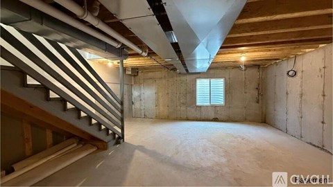 A spacious attic room with wooden stairs and exposed beams.