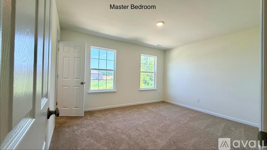 A master bedroom with a carpeted floor and two windows.