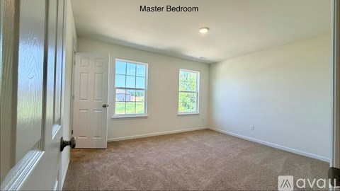 A master bedroom with a carpeted floor and two windows.