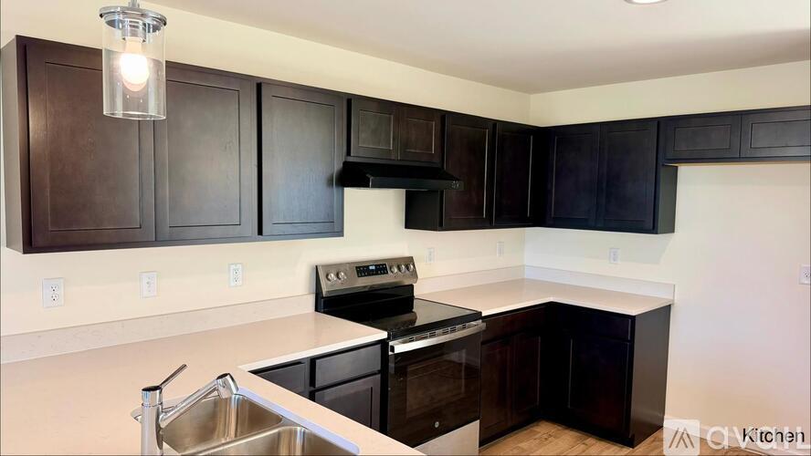 A kitchen with dark brown cabinets and a stainless steel sink.