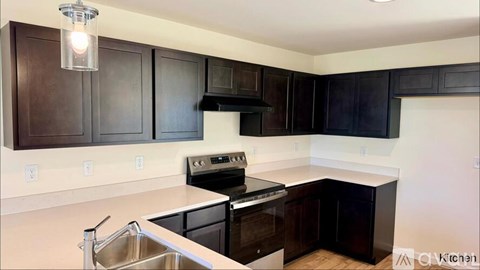 A kitchen with dark brown cabinets and a stainless steel sink.