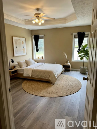 A bedroom with a bed, a ceiling fan, and a rug on the floor.