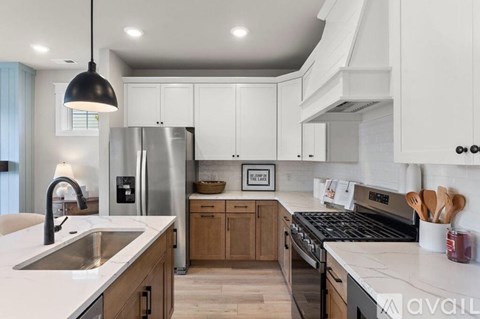 A modern kitchen with white cabinets and a stainless steel refrigerator.