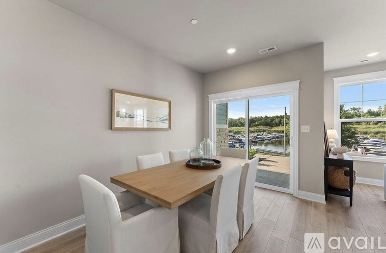 A dining room with a wooden table and white chairs.
