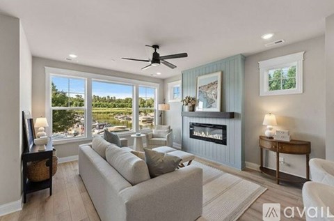 A living room with a grey couch and a fan on the ceiling.