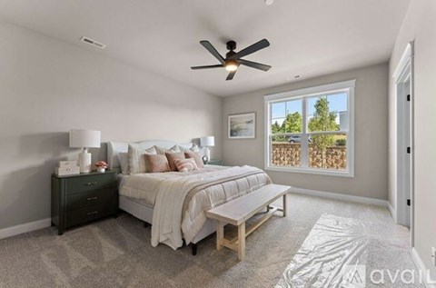 A bedroom with a bed, nightstand, and a window with a view of trees.