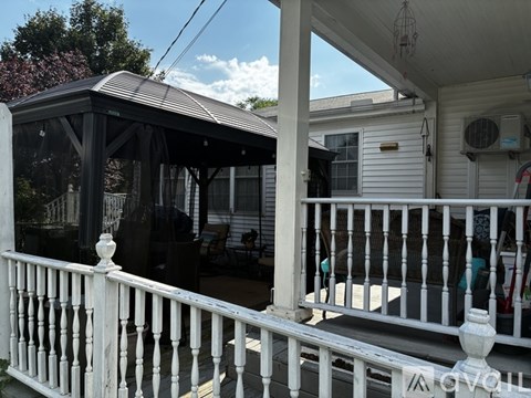 A white porch with a black roof and a white railing.