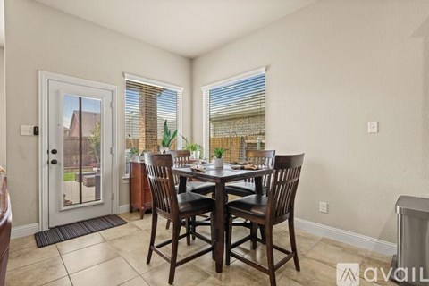 A dining room with a table set for four and a view of a backyard.