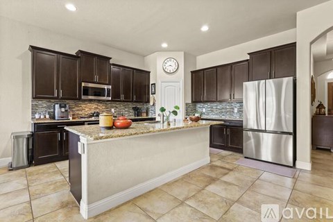 A kitchen with brown cabinets and a marble island.