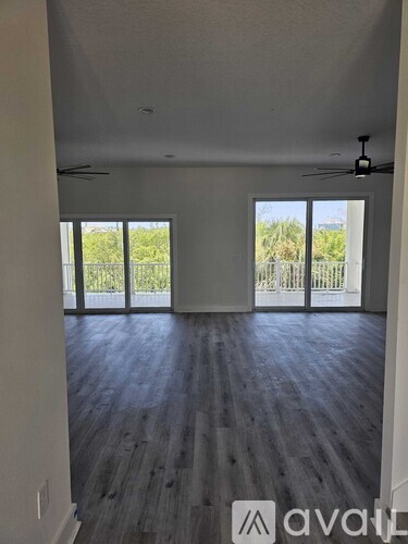A spacious room with wooden flooring and sliding glass doors leading to a balcony.
