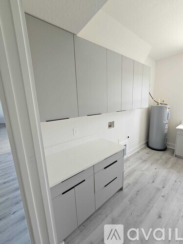 A kitchen with white cabinets and a grey floor.