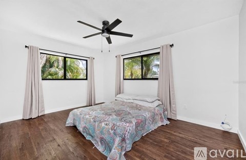 A bedroom with a bed, a ceiling fan, and a window with curtains.