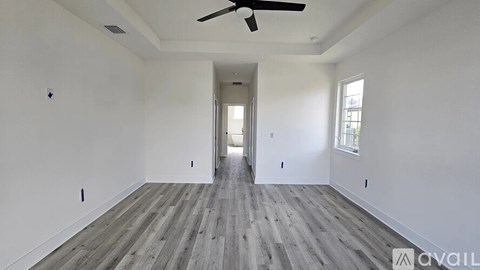 A spacious room with a ceiling fan and wooden flooring.