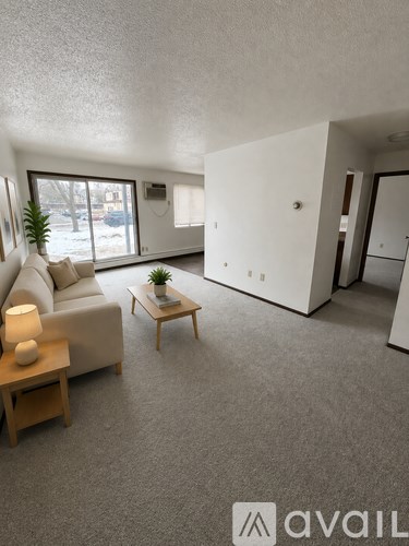 A living room with a couch, a table with a lamp, and a plant on a small table.