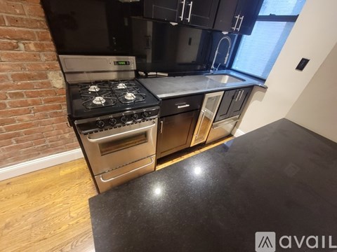 A kitchen with a black countertop and a brick wall.