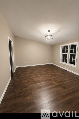 A room with wooden flooring and a window with white blinds.