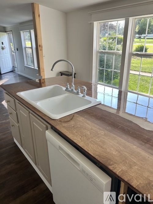 A kitchen with a white sink and brown countertop.