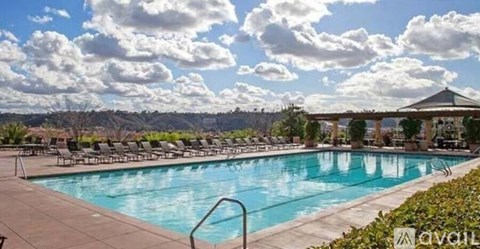 A large outdoor swimming pool surrounded by lounge chairs and umbrellas.