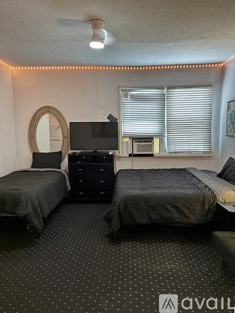 A bedroom with two beds, a dresser, and a mirror.