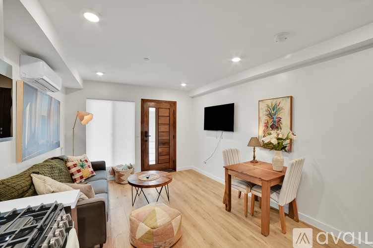 A living room with a couch, a coffee table, a dining table, and a television.