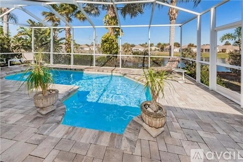 A pool surrounded by a white fence and palm trees.