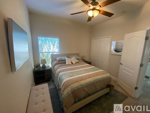 A bedroom with a bed, nightstand, and a ceiling fan.