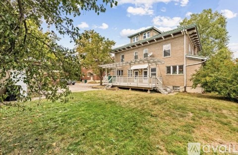 A large house with a porch and a tree in front.
