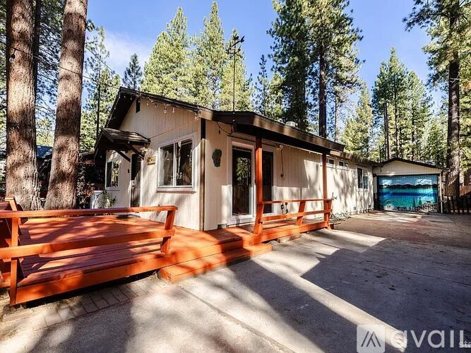 A cabin in the woods with a deck and a garage.