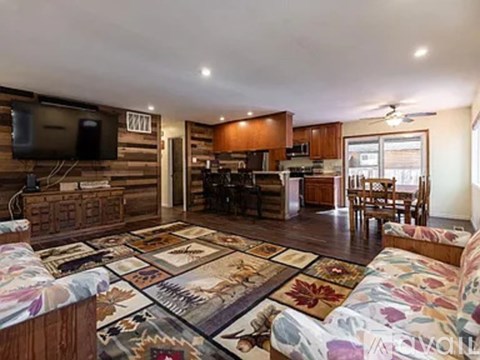 A living room with a rug on the floor and a television on the wall.