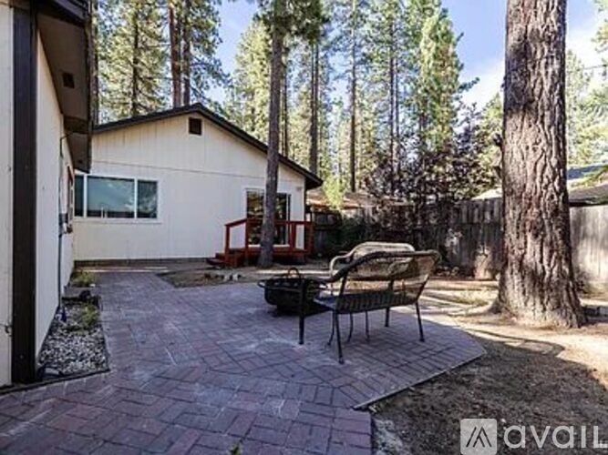 A patio area with a table and chairs is surrounded by trees.
